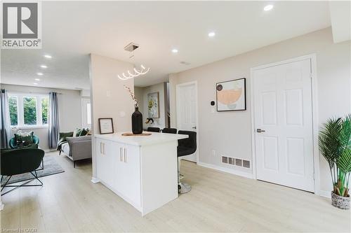 Light-toned wood-finish flooring throughout, white paneled doors, recessed ceiling lighting, and a white kitchen island with modern hardware - 67 Kinzie Avenue, Kitchener, ON - Indoor