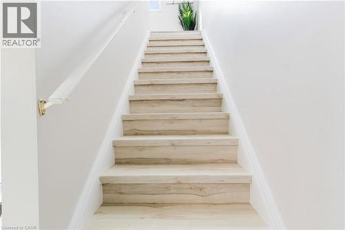 Staircase featuring wood-finish treads and risers, a white handrail, and brass-finish brackets - 67 Kinzie Avenue, Kitchener, ON - Indoor Photo Showing Other Room
