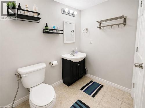 White toilet with bidet attachment, vanity with sink, wall-mounted mirror, and tile flooring - 67 Kinzie Avenue, Kitchener, ON - Indoor Photo Showing Bathroom