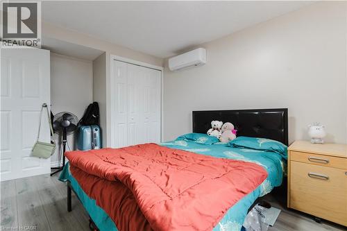 Wood-finish flooring, white paneled doors, and a built-in wall-mounted air conditioning unit - 67 Kinzie Avenue, Kitchener, ON - Indoor Photo Showing Bedroom