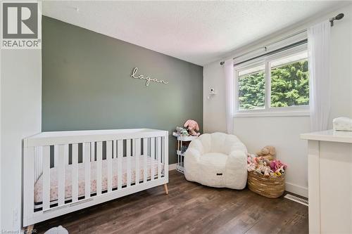 Wood-finish flooring, a window with white trim, a painted accent wall, and white ceiling - 589 Elgin Street N, Cambridge, ON - Indoor Photo Showing Bedroom