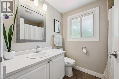 White vanity with an integrated sink, polished chrome faucet, wood-finish flooring, and a sliding window - 589 Elgin Street N, Cambridge, ON - Indoor Photo Showing Bathroom