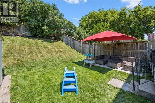 Expansive backyard featuring a lush lawn, mature trees, wood privacy fencing, and a paved patio area - 589 Elgin Street N, Cambridge, ON - Outdoor With Backyard