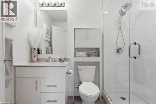White vanity with a light-toned countertop, rectangular mirror, glass-enclosed shower, and built-in shelving - 251 Northfield Drive E Unit# 312, Waterloo, ON 