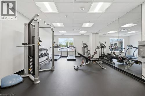 Dedicated fitness space featuring rubber flooring, drop ceiling with integrated lighting, full-height mirrored wall, and multiple windows - 251 Northfield Drive E Unit# 312, Waterloo, ON 