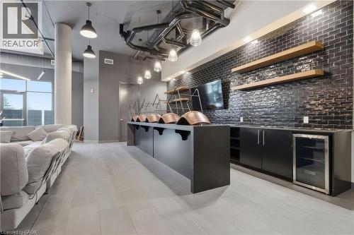 Modern amenity area featuring large format tile flooring, black subway tile accent wall, built-in cabinetry, integrated beverage cooler, and large windows providing natural light - 251 Northfield Drive E Unit# 312, Waterloo, ON 