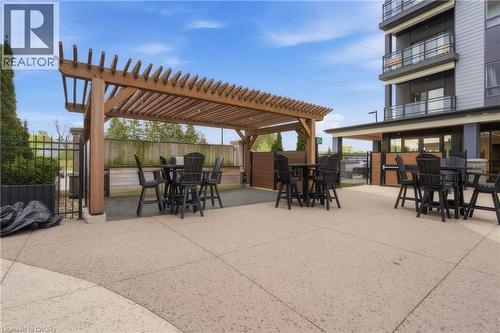 Expansive outdoor patio with a wood pergola, modern concrete surfacing, and surrounding privacy fencing - 251 Northfield Drive E Unit# 312, Waterloo, ON 