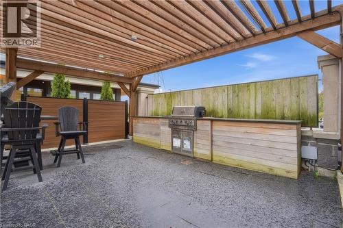 Outdoor patio with a wooden pergola, built-in BBQ station, and dark textured hardscaping - 251 Northfield Drive E Unit# 312, Waterloo, ON 