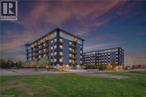 Modern building exterior with multiple balconies, dark grey and light grey paneling, and numerous windows - 251 Northfield Drive E Unit# 312, Waterloo, ON 