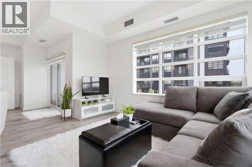 Spacious living area featuring expansive windows, wood-finish flooring, and white walls - 251 Northfield Drive E Unit# 312, Waterloo, ON 