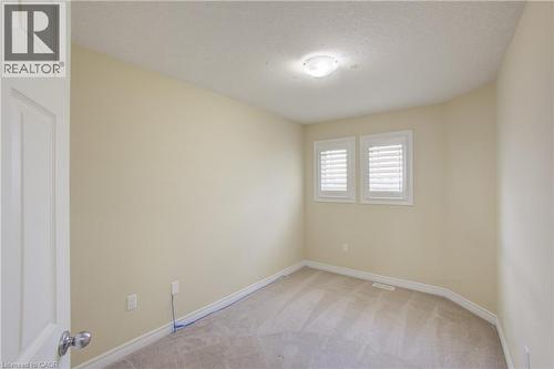Light neutral wall paint, carpeted flooring, overhead flush mount light, two windows with plantation shutters, and a white interior door - 193 Mccann Street, Guelph, ON - Indoor Photo Showing Other Room