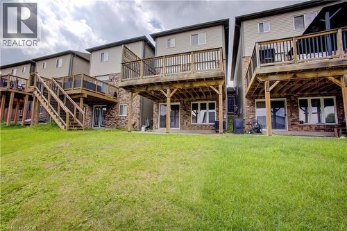 Expansive green space backing to properties featuring brick veneer and siding exteriors, elevated wood decks with railings, and ground-level patio doors - 193 Mccann Street, Guelph, ON - Outdoor With Deck Patio Veranda