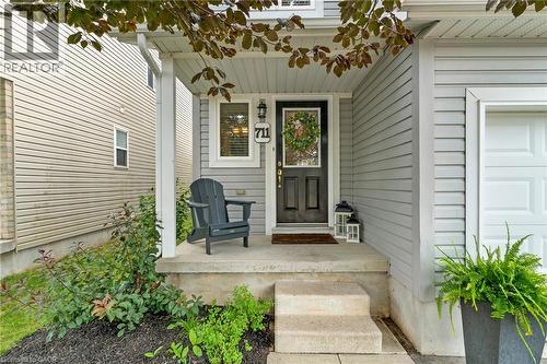Inviting covered porch with concrete steps, light gray siding, and an attached single-car garage - 711 Angler Way, Waterloo, ON - Outdoor
