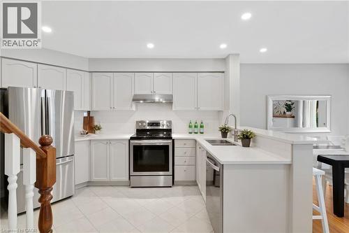 Kitchen featuring white cabinetry, stainless steel appliances, light-toned countertops, tile flooring, and recessed lighting - 711 Angler Way, Waterloo, ON - Indoor Photo Showing Kitchen With Double Sink With Upgraded Kitchen