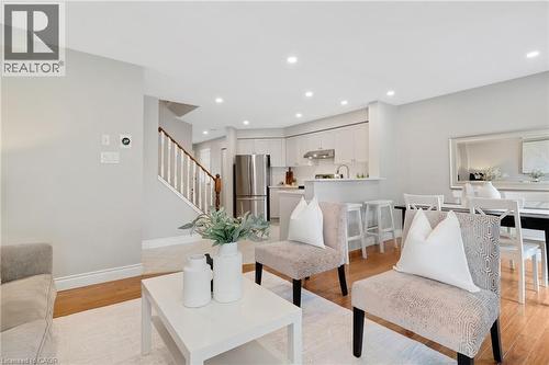 Open-concept living area featuring wood-finish flooring, recessed lighting, and a white painted staircase with wood handrail - 711 Angler Way, Waterloo, ON - Indoor Photo Showing Living Room