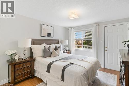 Hardwood flooring, light-toned walls, a window with horizontal blinds, a white paneled door, and a flush mount ceiling light fixture - 711 Angler Way, Waterloo, ON - Indoor Photo Showing Bedroom