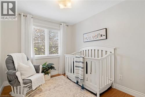 Recessed window with white blinds, wood-finish flooring, white baseboards, and a flush mount ceiling light - 711 Angler Way, Waterloo, ON - Indoor Photo Showing Bedroom