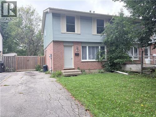 Two-story brick and siding home featuring a manicured front lawn with mature landscaping, a paved driveway with gated side access, and a covered front entrance with stepped entry - 216 Brunswick Crescent, London, ON - Outdoor