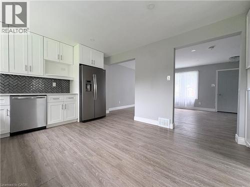 Modern kitchen with white cabinetry, stainless steel appliances, herringbone tile backsplash, and wood-finish flooring - 216 Brunswick Crescent, London, ON - Indoor Photo Showing Kitchen