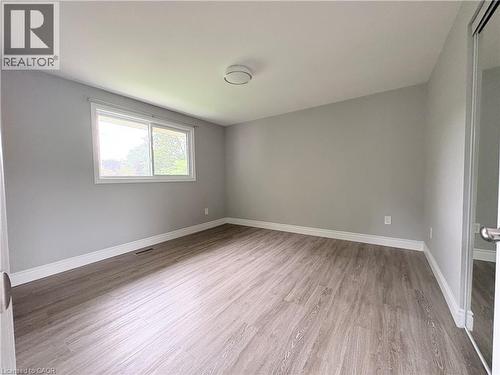 Light gray wall paint, wood-finish flooring, white window trim, white baseboards, and a semi-flush mount ceiling fixture - 216 Brunswick Crescent, London, ON - Indoor Photo Showing Other Room