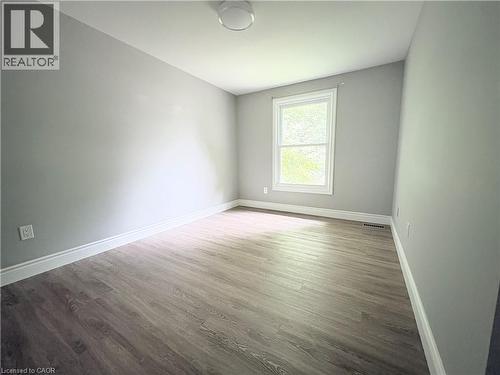 Wood-finish flooring with white trim, a double-hung window, light gray walls, and a flush-mount ceiling light - 216 Brunswick Crescent, London, ON - Indoor Photo Showing Other Room