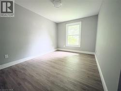 Wood-finish flooring with white trim, a double-hung window, light gray walls, and a flush-mount ceiling light - 