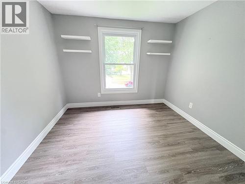 Neutral gray wall color, wood-finish flooring, white window trim, and two built-in floating shelves - 216 Brunswick Crescent, London, ON - Indoor Photo Showing Other Room
