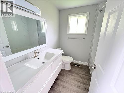 Bathroom featuring wood-finish flooring, a white vanity with an integrated sink, a rectangular framed mirror, and a window - 216 Brunswick Crescent, London, ON - Indoor Photo Showing Bathroom