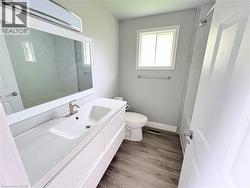 Bathroom featuring wood-finish flooring, a white vanity with an integrated sink, a rectangular framed mirror, and a window - 