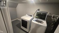 Dedicated laundry area with sloped ceiling and light gray walls - 