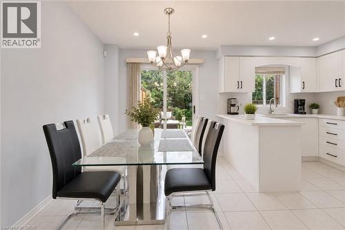 White kitchen cabinetry with black hardware, white countertops, tile flooring, recessed lighting, and a sliding glass door - 1793 Creek Way, Burlington, ON - Indoor Photo Showing Dining Room