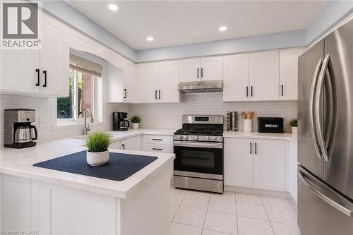 White cabinetry with black hardware, stainless steel appliances, white tile flooring, white subway tile backsplash, and recessed lighting - 1793 Creek Way, Burlington, ON - Indoor Photo Showing Kitchen With Stainless Steel Kitchen