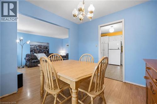 Dining area featuring wood-finish flooring, a decorative ceiling light fixture, and an open doorway to the kitchen - 11 Kimbermount Drive, St. Catharines, ON - Indoor Photo Showing Dining Room