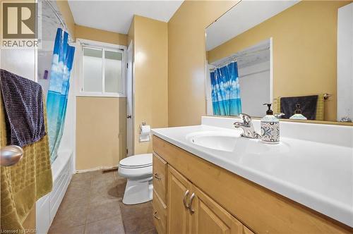 Bathroom featuring a single vanity with a white countertop and light wood-finish cabinetry, a mirror, a toilet, a tub, and a window - 11 Kimbermount Drive, St. Catharines, ON - Indoor Photo Showing Bathroom
