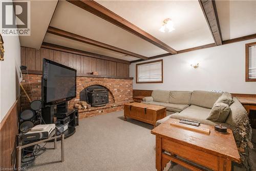 Spacious living area featuring a brick fireplace surround, wood paneling, and exposed ceiling beams - 11 Kimbermount Drive, St. Catharines, ON - Indoor Photo Showing Living Room With Fireplace