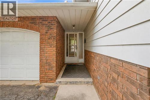 Brick and siding exterior featuring an arched garage door, covered entryway, and glass-paneled front door - 11 Kimbermount Drive, St. Catharines, ON - Outdoor With Exterior