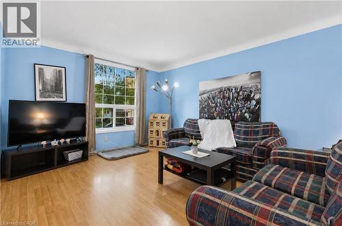 Living area featuring light wood-finish flooring, a large window with white framing, and blue painted walls - 11 Kimbermount Drive, St. Catharines, ON - Indoor Photo Showing Living Room