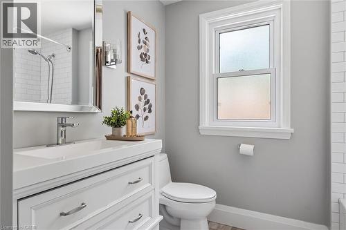 White vanity with integrated sink, chrome faucet, wall-mounted mirror, white subway tile shower surround, and window with white trim - 90 Dean Avenue, Guelph, ON - Indoor Photo Showing Bathroom