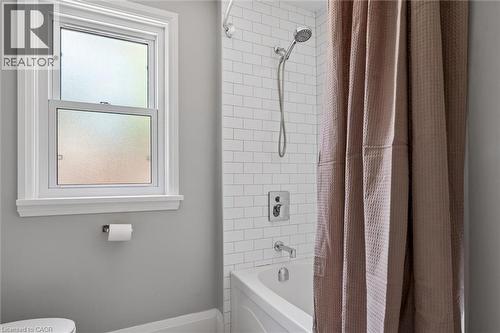 Bathtub with subway tile surround, polished chrome fixtures, and a double-hung window with privacy glazing - 90 Dean Avenue, Guelph, ON - Indoor Photo Showing Bathroom