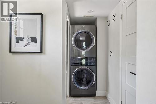 Built-in stacked washer and dryer, recessed overhead lighting, and paneled storage cabinetry - 90 Dean Avenue, Guelph, ON - Indoor Photo Showing Laundry Room