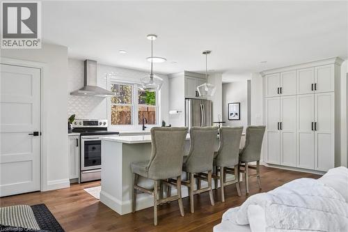 Spacious kitchen featuring an island with seating, stainless steel appliances, white cabinetry, and wood-finish flooring - 90 Dean Avenue, Guelph, ON - Indoor