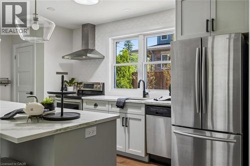 Kitchen featuring stainless steel appliances, white cabinetry, a kitchen island with stone-finish countertop, and a contemporary pendant light fixture - 90 Dean Avenue, Guelph, ON - Indoor Photo Showing Kitchen