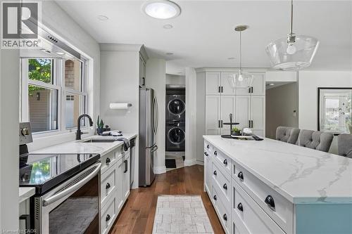 Kitchen featuring an expansive center island with stone-finish countertop, pendant lighting, stainless steel appliances, and wood-finish flooring - 90 Dean Avenue, Guelph, ON - Indoor Photo Showing Kitchen With Upgraded Kitchen