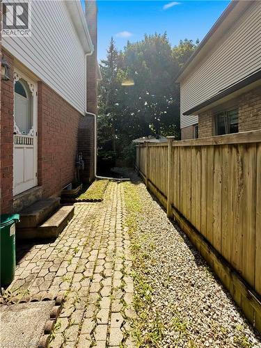 Paver stone pathway leading to a treed area, bordered by a wood fence and gravel landscaping - 512 Hawthorne Crescent, Milton, ON - Outdoor With Exterior