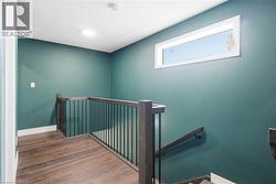 Wood-finish flooring with a contrasting baseboard, complemented by a horizontal window and recessed ceiling lighting - 