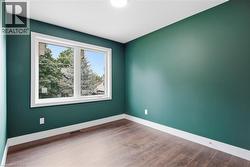 Wood-finish flooring, white trim, and a window with white casing - 