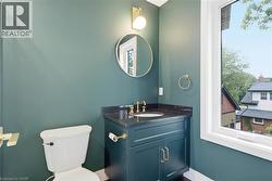 Vanity with a dark countertop and gold-toned fixtures, circular mirror, and a window providing natural light - 