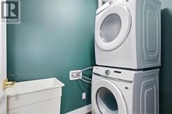 Laundry area with a utility sink, wall-mounted faucet, and stacked appliance space - 