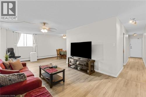 Wood-finish flooring throughout, bright white walls, and track lighting in the hallway - 975 Warwick Court Unit# 708, Burlington, ON - Indoor Photo Showing Living Room