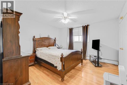 Wood-finish flooring, ceiling fan with light fixture, window with blinds, and white walls - 975 Warwick Court Unit# 708, Burlington, ON - Indoor Photo Showing Bedroom